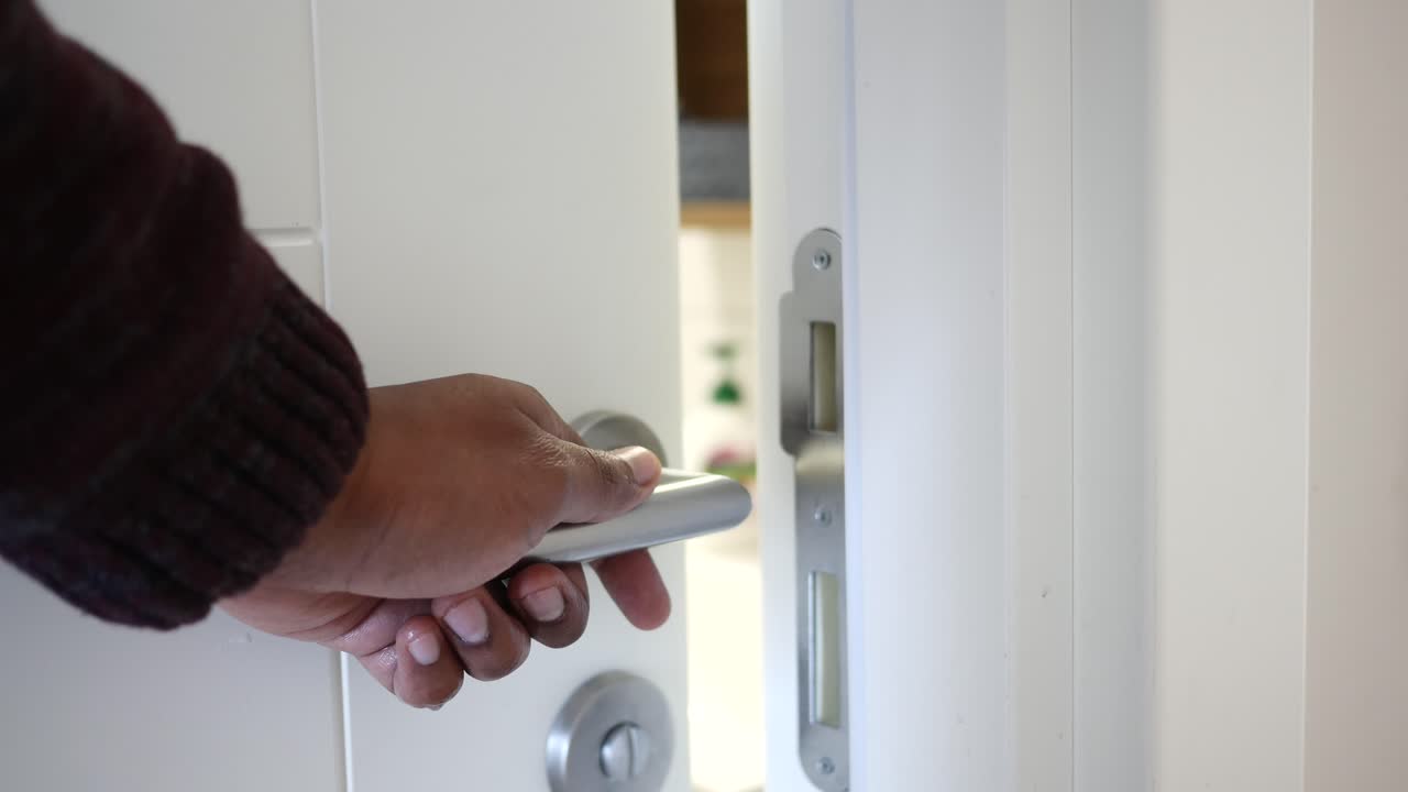 una persona abre una puerta blanca a un baño.
