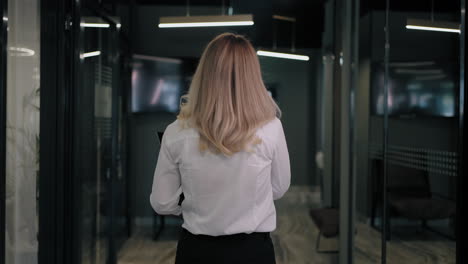 the camera follows the corridor behind a blonde in a white shirt of a business woman