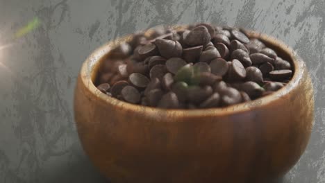 Animation-of-light-over-chocolate-crisps-in-bowl-over-grey-background