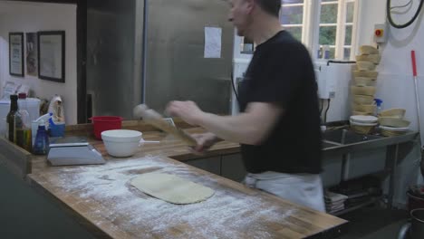 hombre trabajando con masa, usando un rodillo en la encimera de madera
