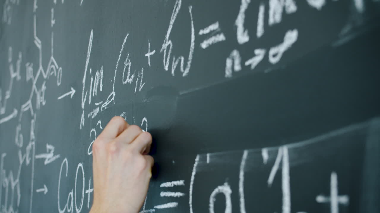 Person writing equations on a chalkboard