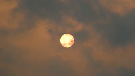 Strawberry-full-moon-with-fast-moving-clouds-passing-across-overcast-night-sky