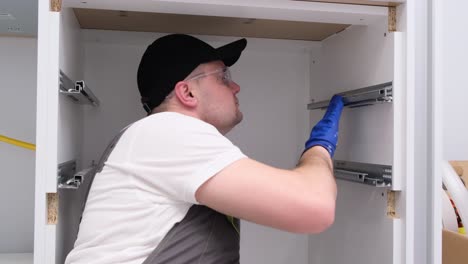 the craftsman installs fittings for kitchen drawers