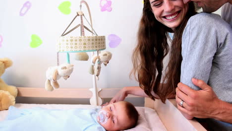 Happy-parents-watching-over-baby-son-in-crib-