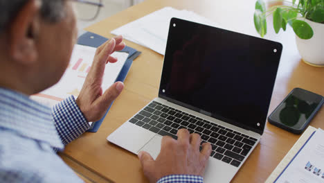 Video-of-senior-biracial-man-sitting-at-using-laptop-for-video-call-at-home,-copy-space-on-screen