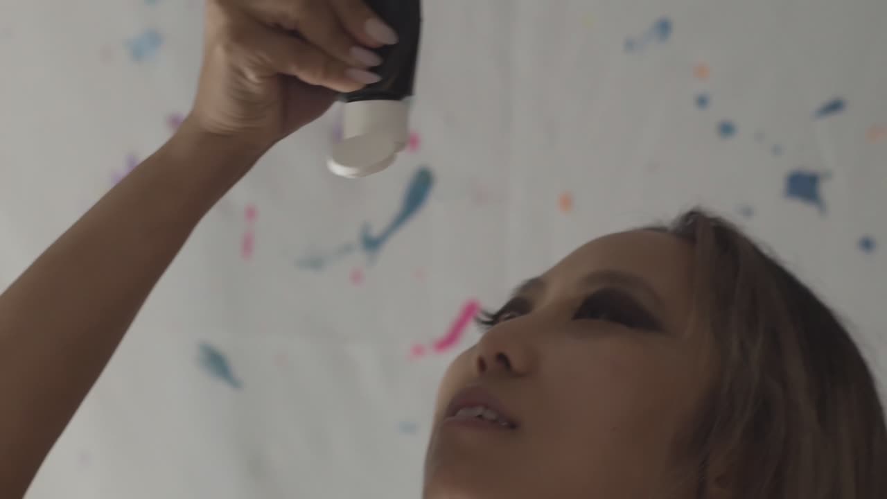 joven asiática vertiendo pintura negra en su cuerpo, cámara lenta de cerca