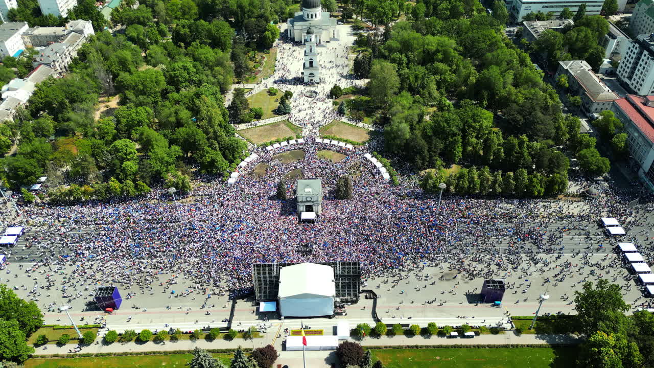 CHISINAU, MOLDOVA - 21 MAY, 2023: Aerial drone view of the rally in support of the country's European integration in Chisinau, Moldova. Thousands of people in the city downtown, greenery, EU and national flags, central park