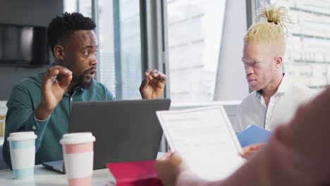 diverse business people discussing with documents in creative office