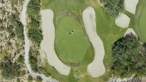 Two-golfers-putting-on-the-green,-top-down-spin