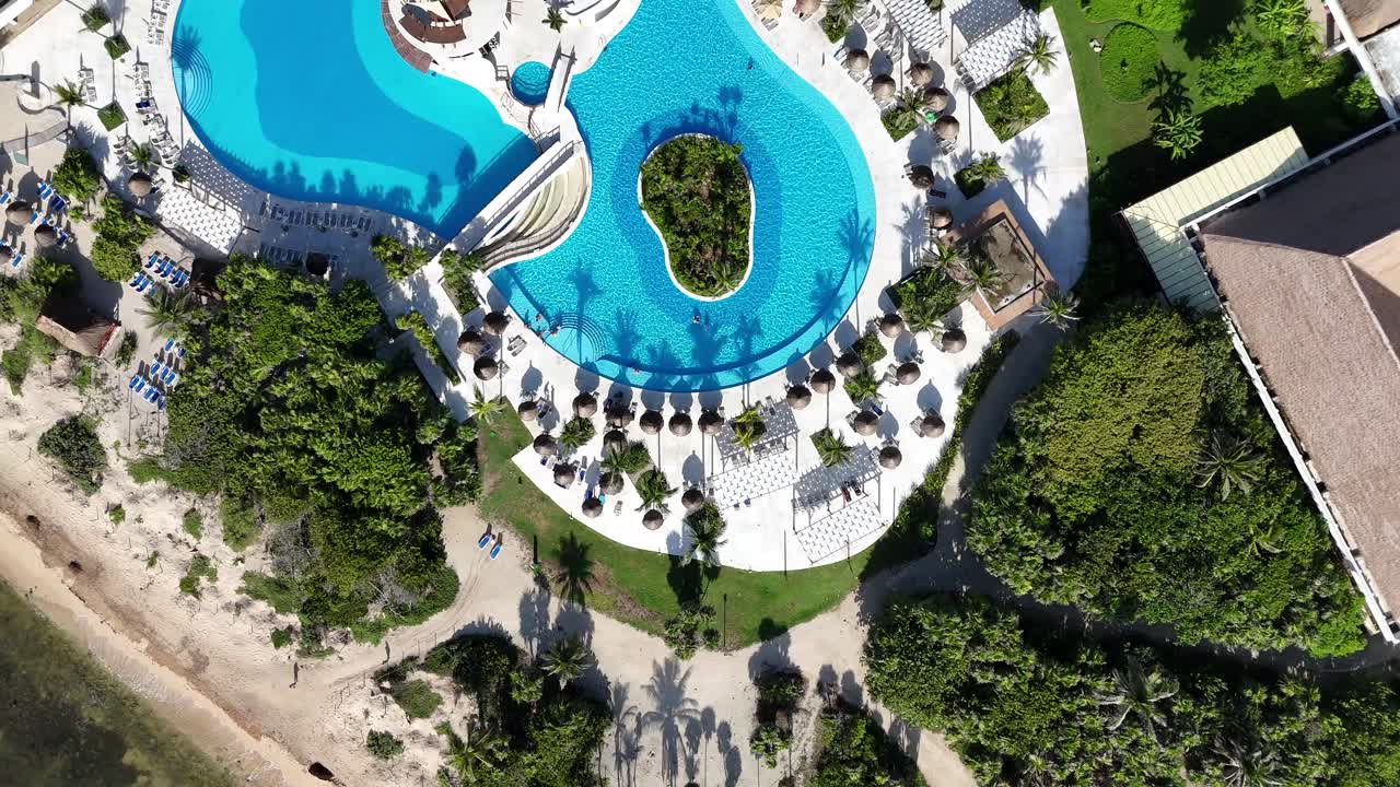 Breathtaking aerial flyover from Caribbean beach to luxury resort pool. Crystal-blue water, palm trees, and tropical paradise vibes captured in cinematic 4K drone footage