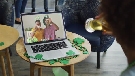 hombre tomando cerveza en una llamada de video portátil celebrando el día de san patricio con amigos