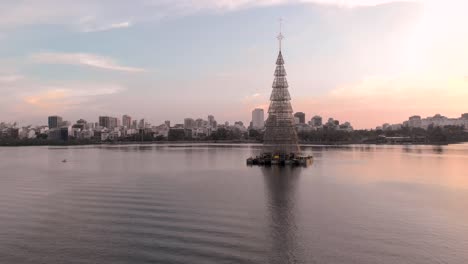 closing in on the worlds tallest floating christmas tree of 2018 in rio de janeiro in the city lake with an amazing colourful sunset and ipanema neighbourhood in the background