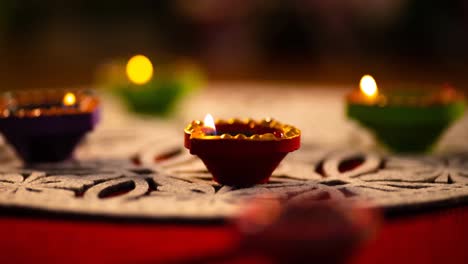 video of glowing lit diwali candles in circle on patterned red and white surface