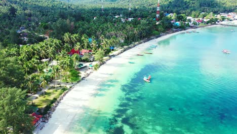 Beautiful-turquoise-lagoon-with-abstract-patterns-of-coral-reef-under-clear-water-washing-white-sandy-beach-with-palm-trees-in-Thailand