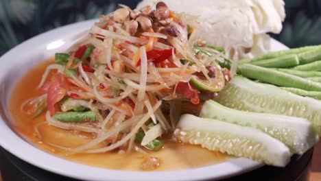 Authentische-Thailändische-Küche,-Somtam,-Papaya-Salat-Mit-Süß-saurer-Sauce,-Frisch-Zubereitet-Auf-Einem-Weißen-Drehteller-Aus-Nächster-Nähe