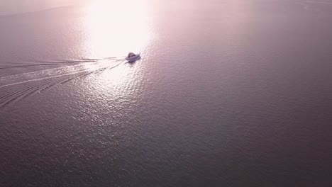 aerial speed boat chasing and following by the drone at golden hour sunrise