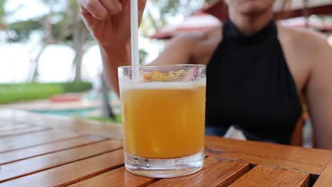 person sipping a cocktail at a wooden table