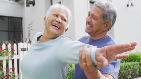 Portrait-of-happy-senior-diverse-couple-dancing-in-garden