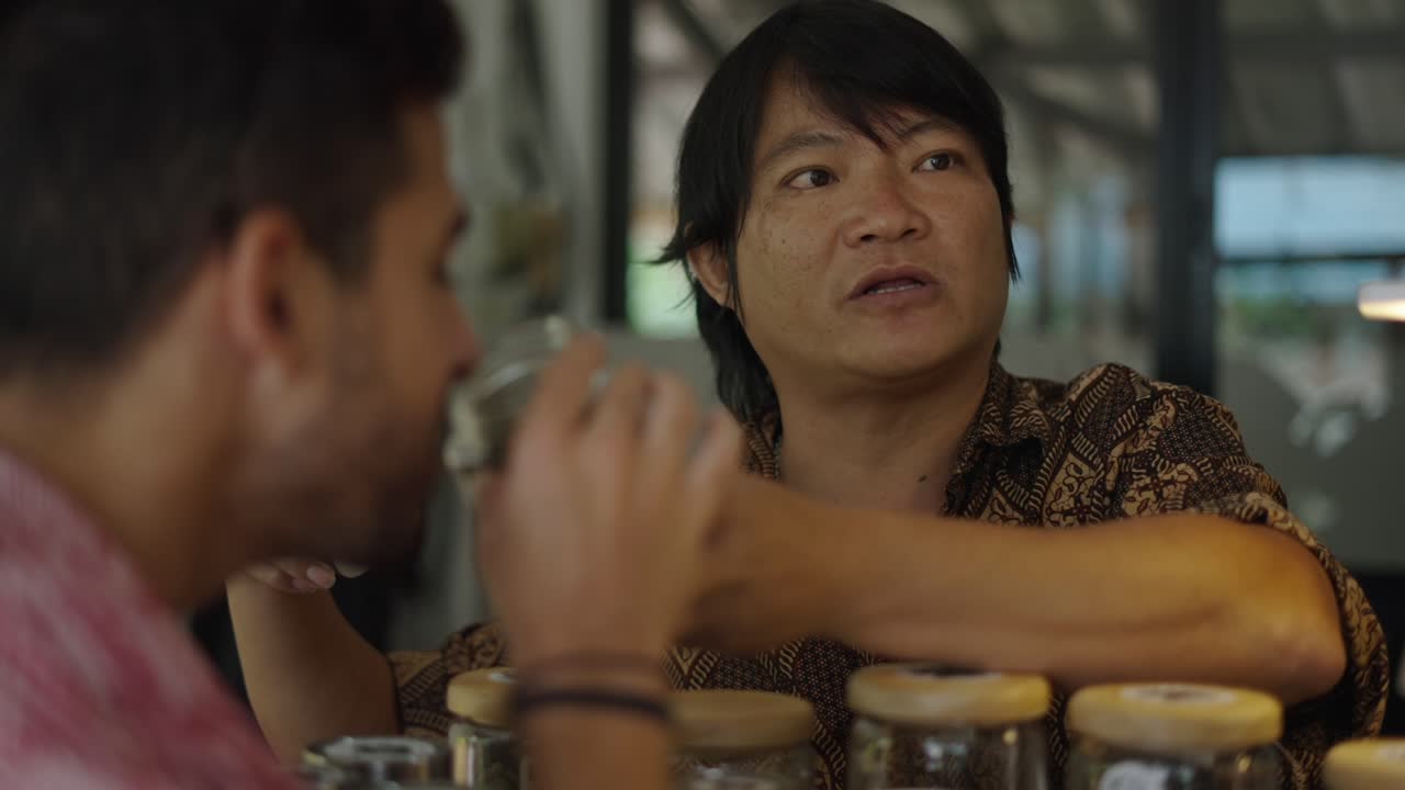 Man interacting with jars of products, possibly herbs or spices, and a customer