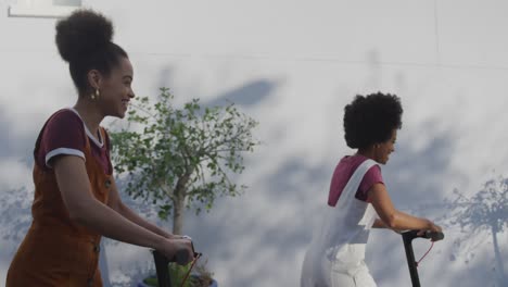 Two-mixed-race-women-riding-electric-scooter