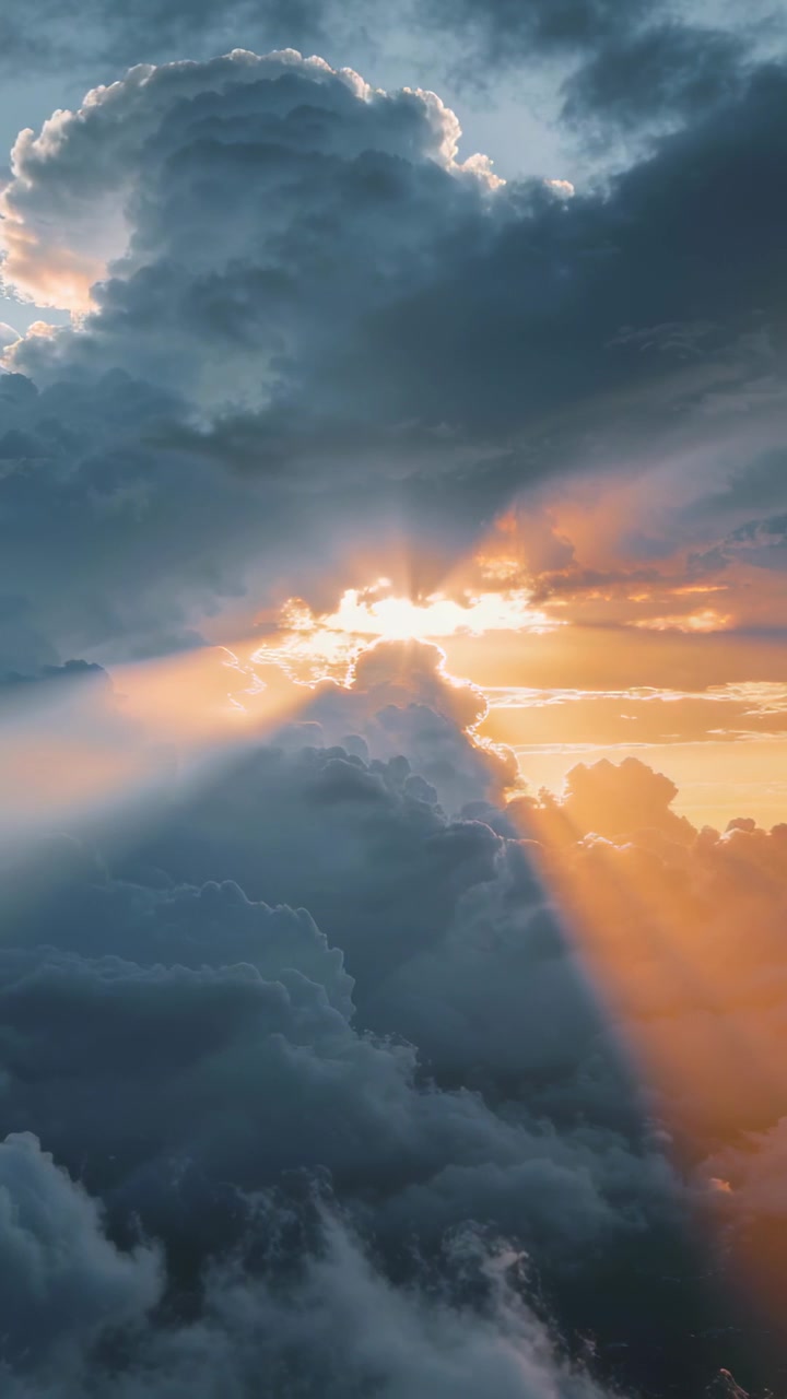 Video verticale: Sole che emerge trafiggendo una nuvola imponente, proiettando raggi dorati attraverso una fessura al tramonto.