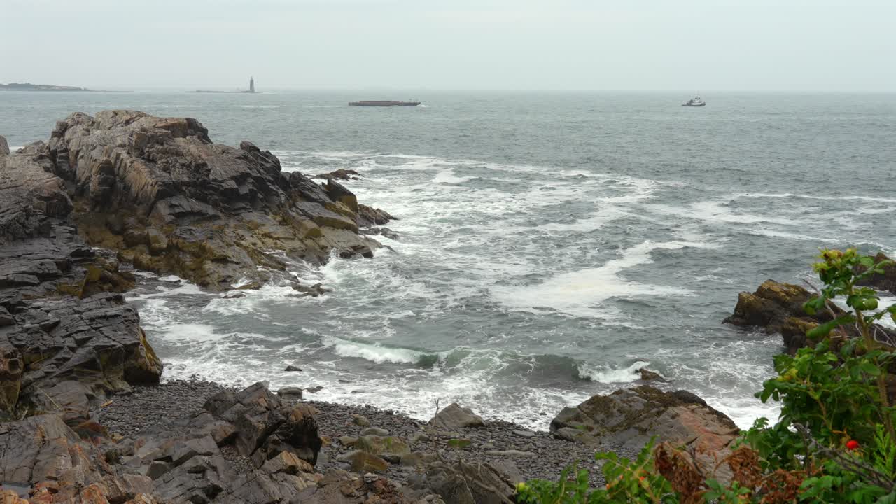 A high angle view of the ocean waves on the rocky shore along the coast of Maine on a foggy day.