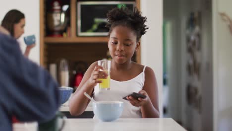 feliz pareja de lesbianas caucásicas y su hija afroamericana desayunando en la cocina