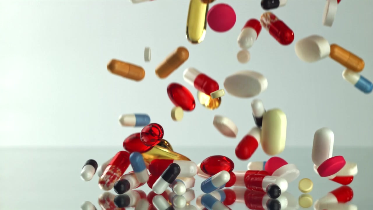 Various Colorful Pills and Capsules Falling in Slow Motion