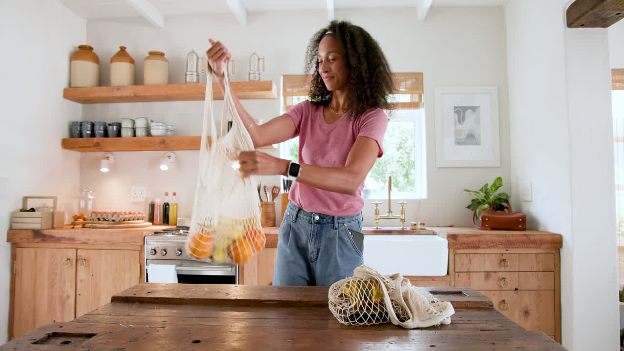 Unpacking groceries from reusable bags, woman smiling in kitchen, at home