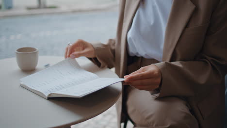 businesswoman hands turning pages notebook in urban coffee house close up.