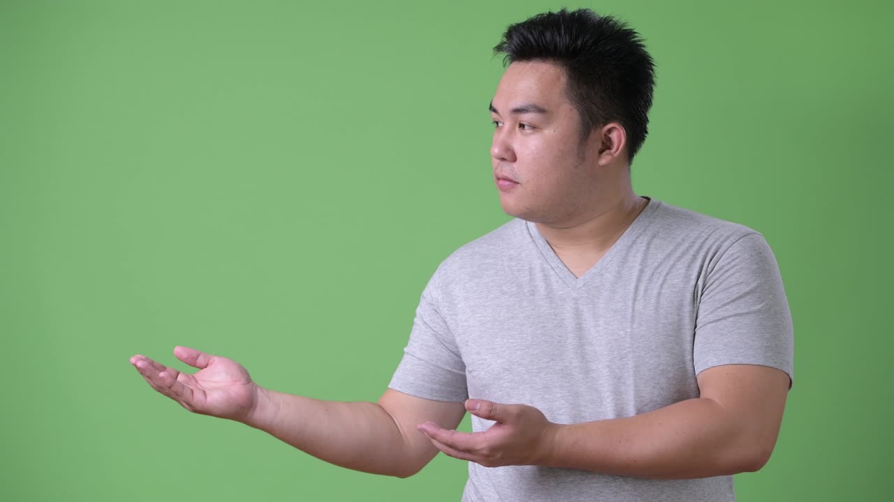 초록색 배경에 젊은 잘생긴 과체중 아시아인