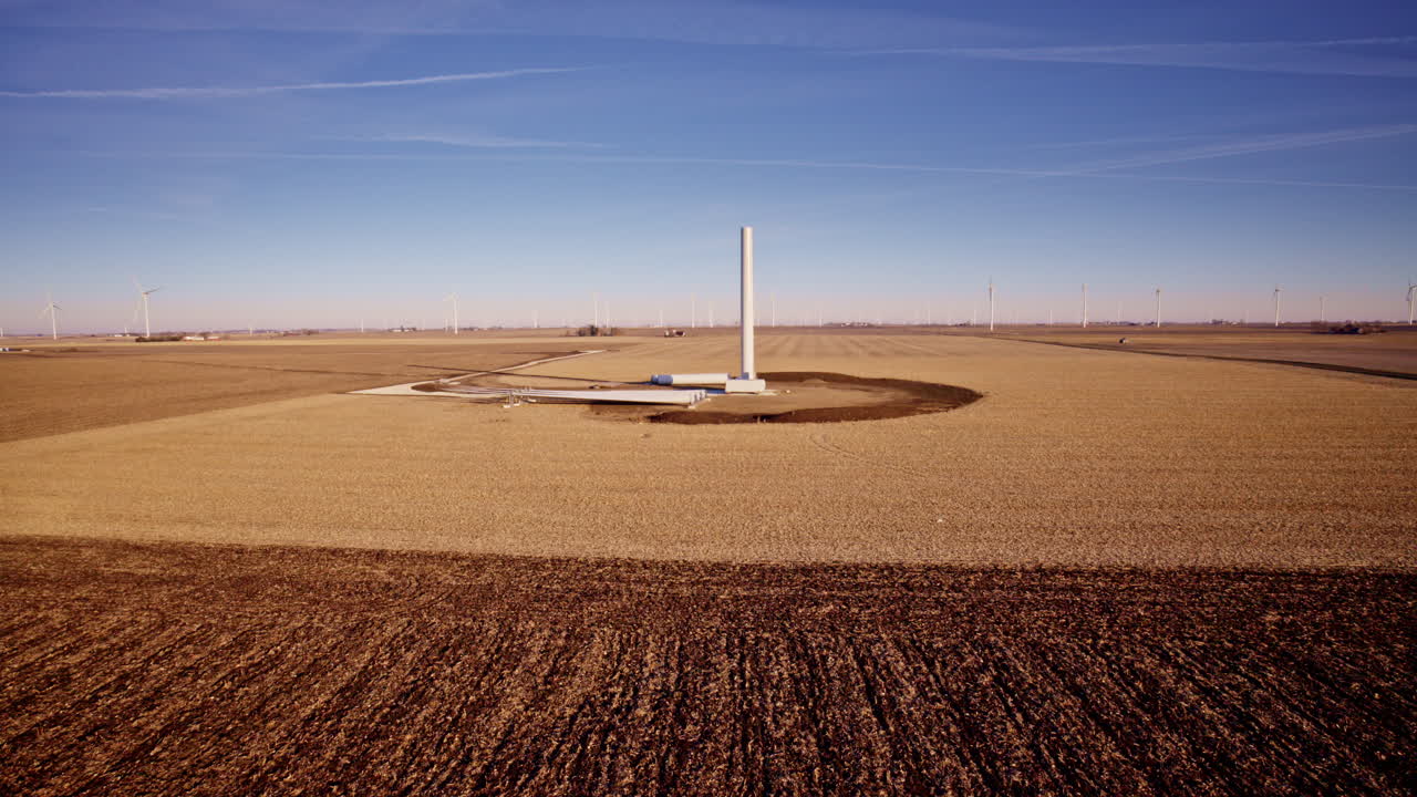 Drone circling towering windmills rising from rural landscape