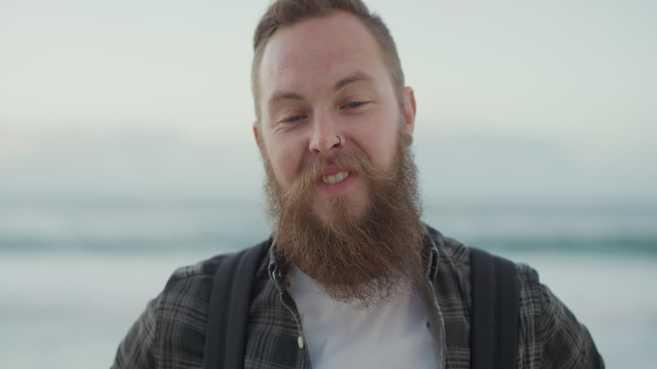 retrato de un hermoso hombre barbudo sonriendo mirando a la cámara en la playa disfrutando de un estilo de vida positivo hermoso hombre hipster en la orilla del mar