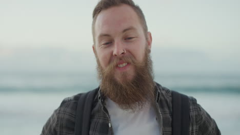 portrait-of-handsome-bearded-man-smiling-looking-at-camera-on-beach-enjoying-positive-lifestyle-handsome-hipster-male-at-seaside