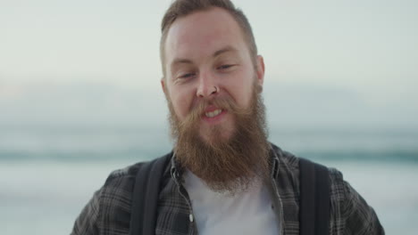 Retrato-De-Un-Apuesto-Hombre-Barbudo-Sonriendo-Mirando-La-Cámara-En-La-Playa-Disfrutando-De-Un-Estilo-De-Vida-Positivo-Un-Apuesto-Hombre-Hipster-En-La-Playa