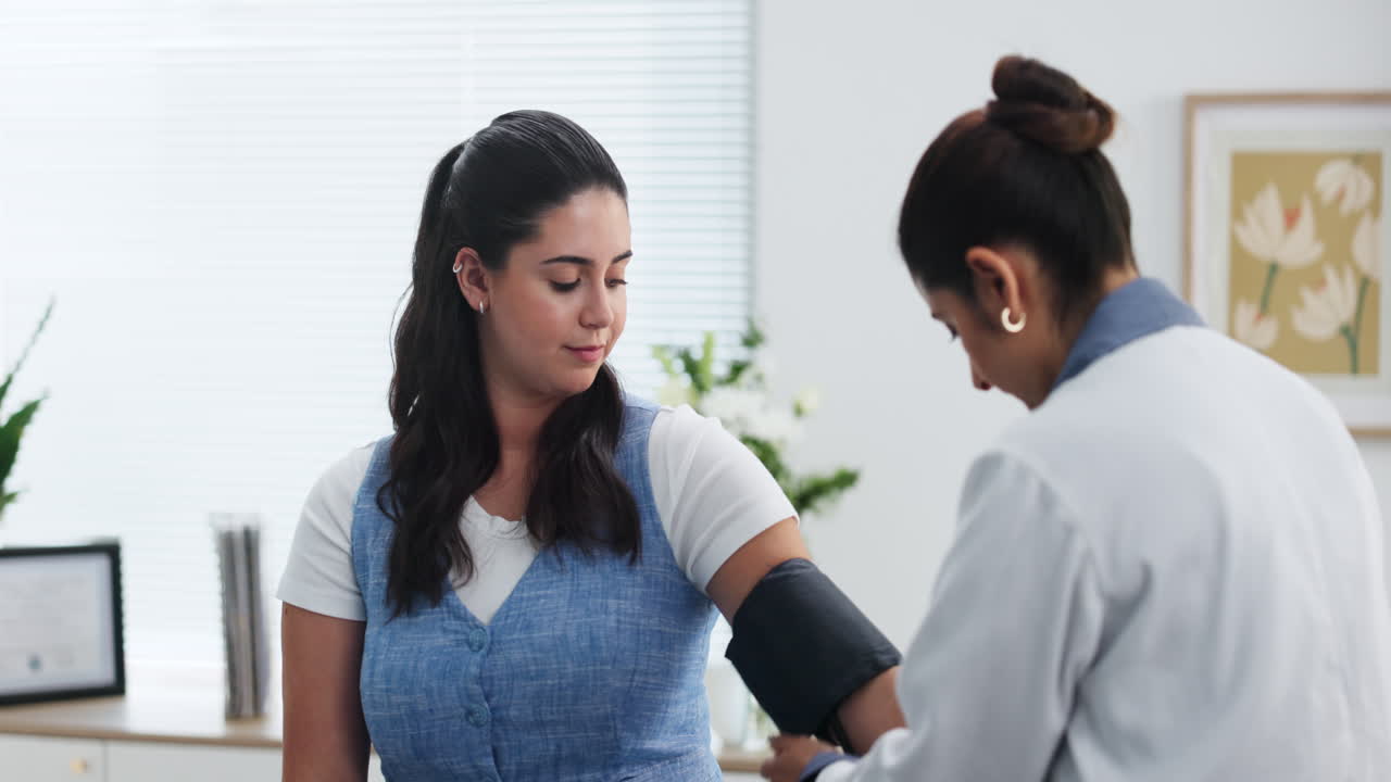 Female Doctor Taking Patient's Blood Pressure in Clinic