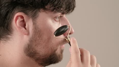 man using a jade roller for facial massage