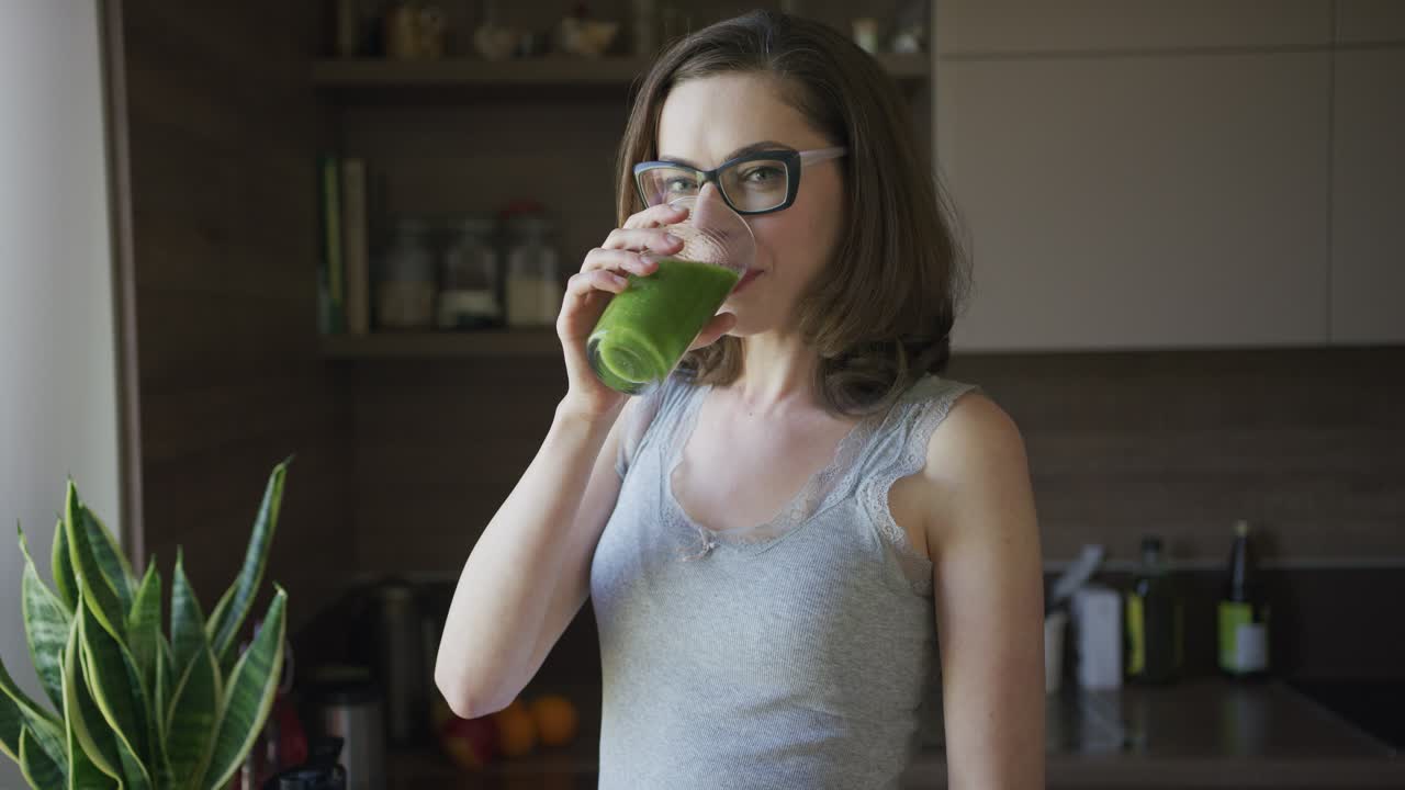 Mulher jovem a beber um smoothie em casa.