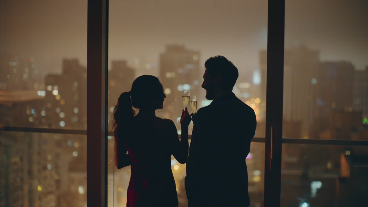 조명 된 도시 를 지켜보는 실루 커플 이 파노라마 호텔 에서 안경을 걱거리고 있다