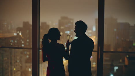 조명 된 도시 를 지켜보는 실루 커플 이 파노라마 호텔 에서 안경을 걱거리고 있다