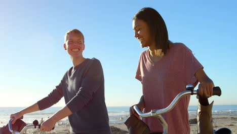 Happy-couple-talking-to-each-other-while-walking-on-the-coast-with-bicycle-4k