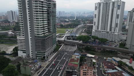 Drone-Vuela-Sobre-Una-Autopista-Con-Mucho-Tráfico-En-Kuala-Lumpur,-Malasia:-Se-Pueden-Ver-Altos-Edificios-De-Apartamentos-Y-Muchas-Casas-A-Lo-Lejos