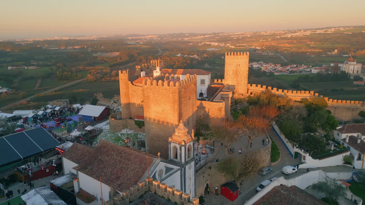 Castle towers overlooking village with red-tiled rooftops panoramic aerial view