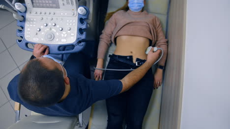 male doctor checks the female patient at ultrasound equipment. kidneys examination on ultrasonic machine. top view.