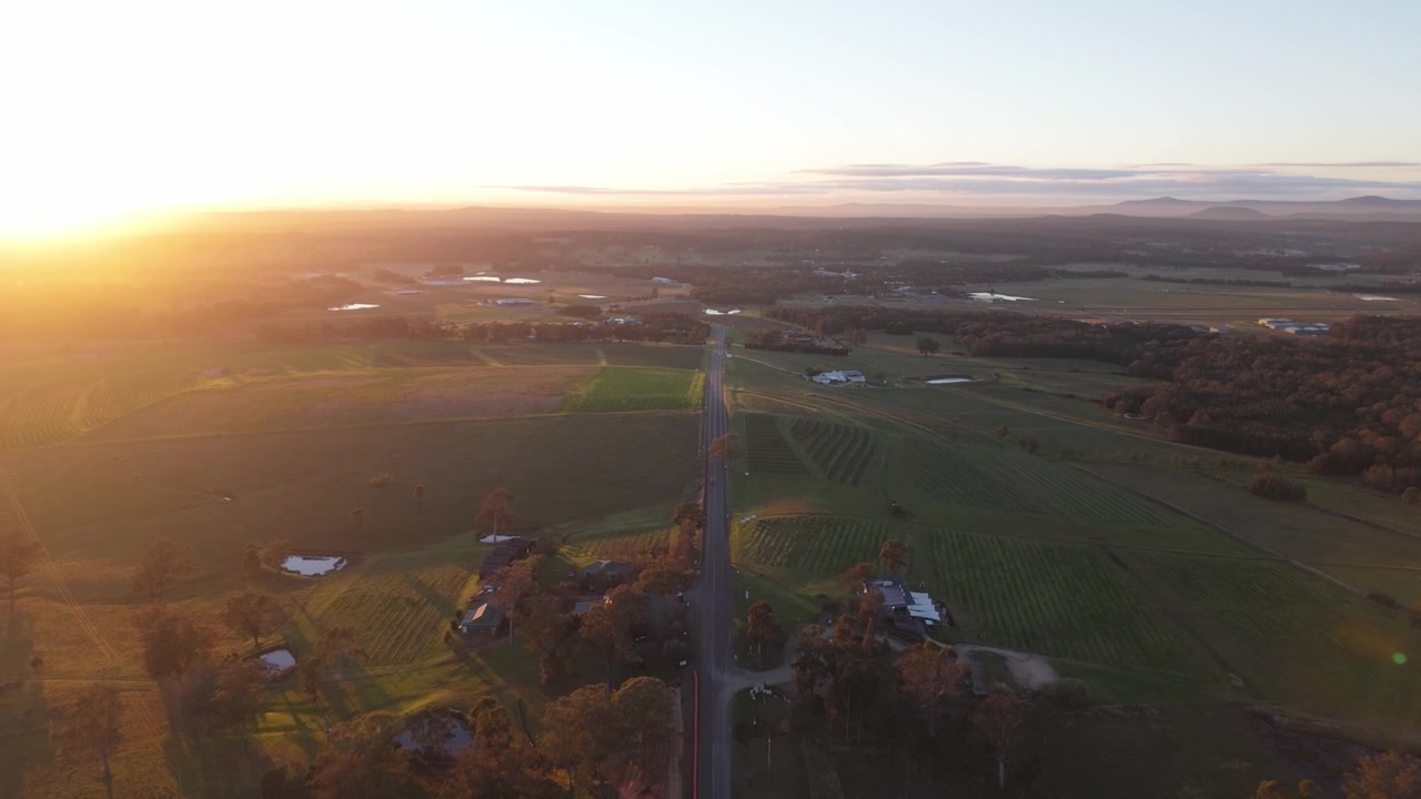Aerial sunrise over Hunter Valley farmland and country road with vibrant warm sunlight cresting landscape, Newcastle NSW Australia