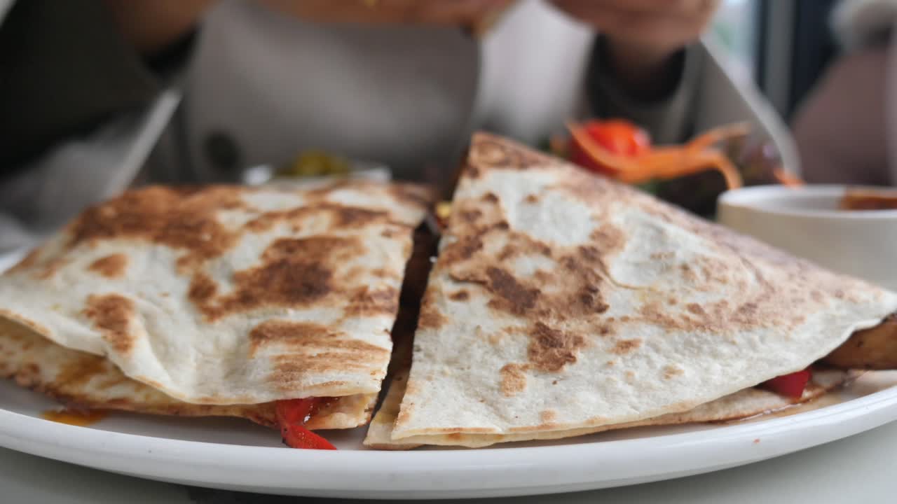 Close-up of Hands Dipping a Piece of Quesadilla into Sauce