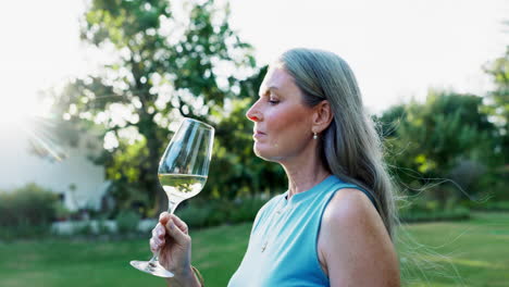mujer mayor disfrutando del vino en el jardín