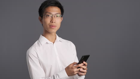 Asian man using smartphone and showing ok gesture.