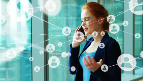 Animation-of-network-of-connections-with-icons-over-caucasian-businesswoman-talking-on-smartphone