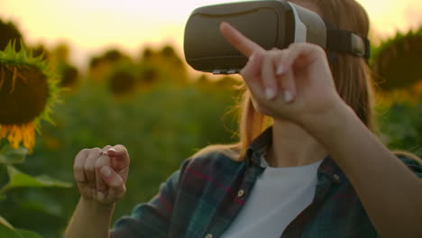 a young girl uses vr glasses on the field with sunflowers in sunny day. these are modern technologies in summer evening.